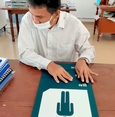 School teacher testing a braille sign to ensure tactile readability.